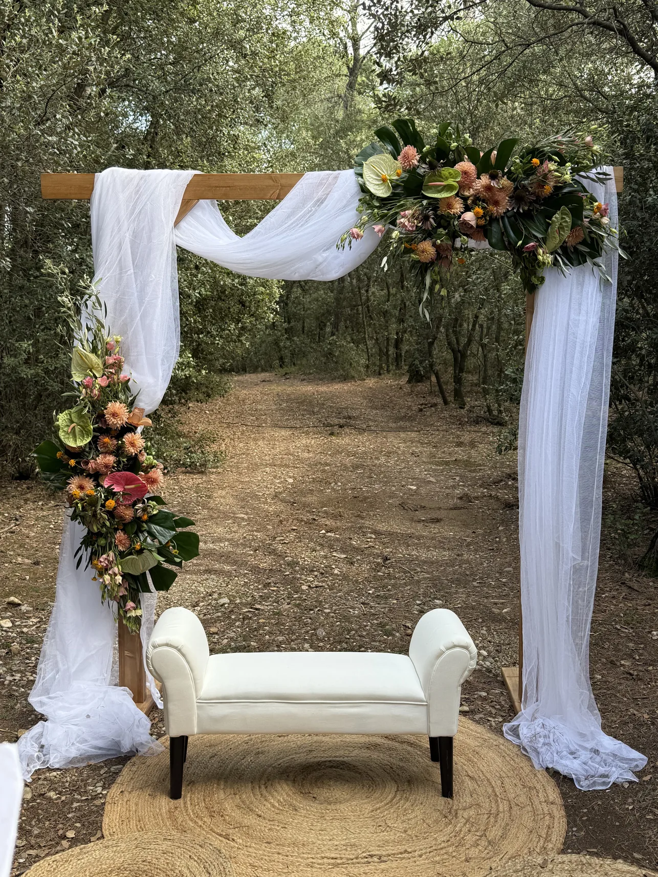 Ceremonia de boda al aire libre con estructura floral y telas blancas