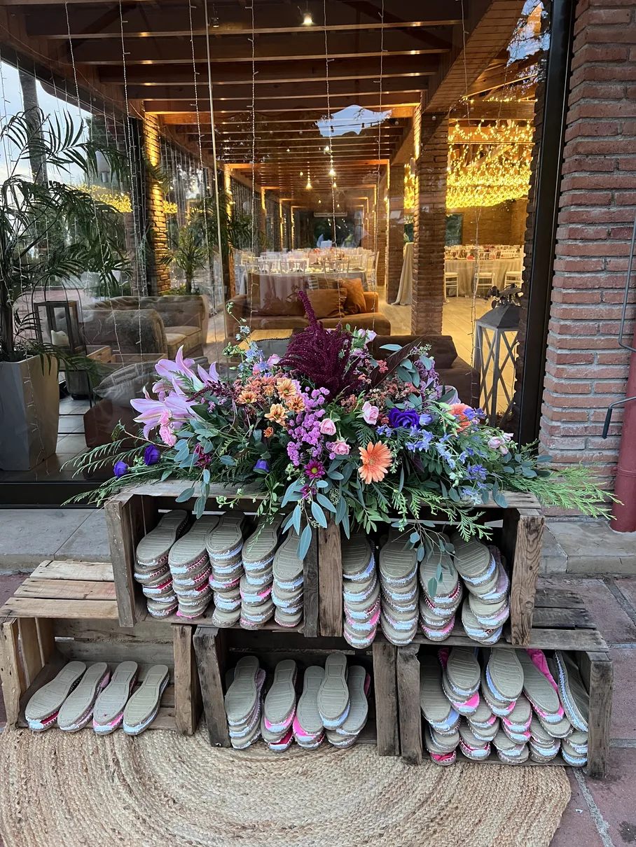 Rincón de zapatillas para invitados con decoración floral en una boda